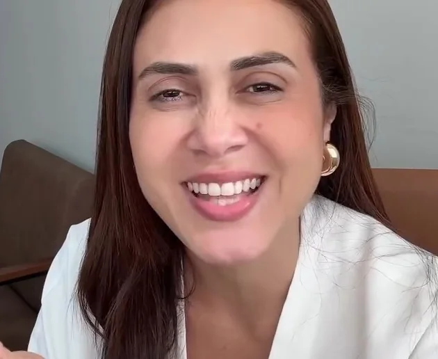 Rogéria Valentim rindo, à mesa do escritório, em um quadro de vídeo